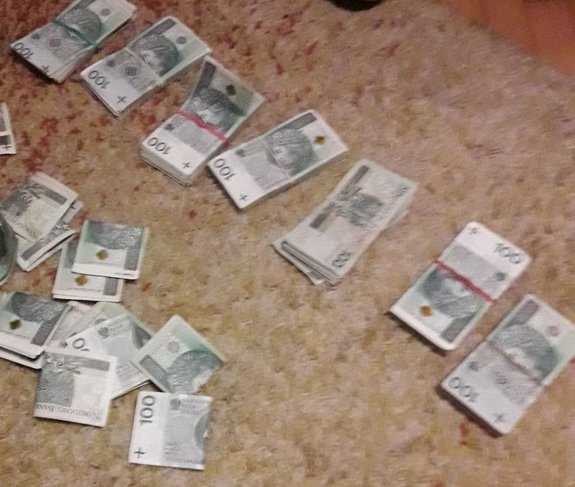 Część odzyskanych przez funkcjonariuszy pieniędzy.  Banknoty leżą na dywanie w większości posegregowane po kilkaset złotych.