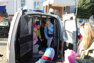 Kilka dzieci siedzi w radiowozie w części przeznaczonej do przewozu osób zatrzymanych