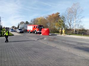 Miejsce wypadku drogowego, jezdnia na której po prawej stronie znajduje wóz strażacki. Przed wozem ustawiony jest parawan z napisem Policja