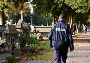 Policjant przechodzi alejką cmentarną