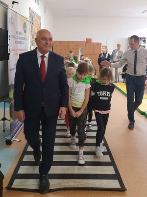 wójt gminy Mielec pokazuje dzieciom jak należy prawidłowo przejść przez jezdnię