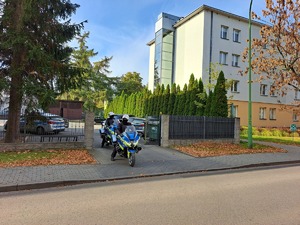 na fotografii motocykle wyjeżdżają z parkingu komendy Policji na drogę
