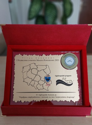 zdjęcie przedstawia Certyfikat dla Miasta Przemyśl przyznający  honorowy tytuł „I Najbezpieczniejsze Miasto Powiatowe w Polsce 2021” wraz z pamiątkową statuetką, oraz dyplom za podejmowanie wysiłków w działaniu na rzecz poprawy bezpieczeństwa na drogach
