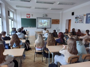 Uczniowie licealnej klasy pierwszej oglądają wyświetlany na interaktywnej tablicy film.
