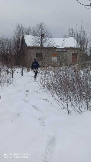 na zdjęciu policjant sprawdzający pustostan w czasie zimy