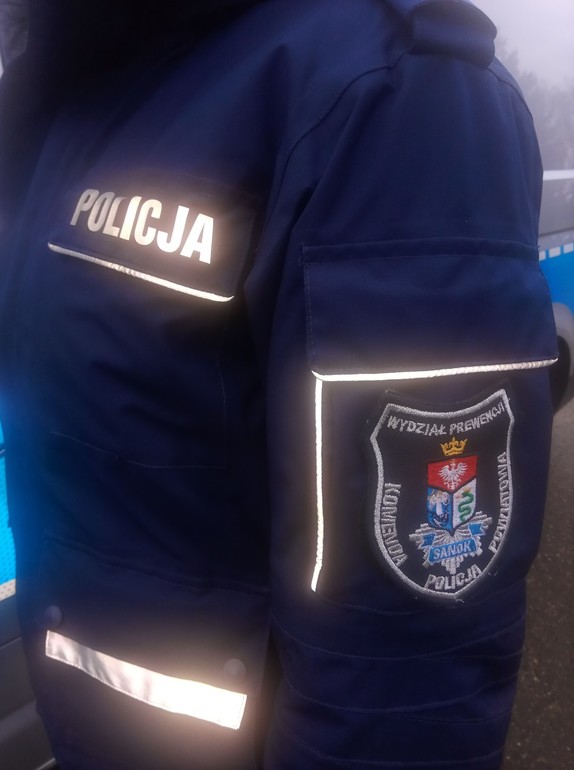 Umundurowany policjant z widoczną na rękawie naszywką Wydział Prewencji Komendy Powiatowej Policji w Sanoku