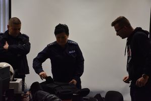 Policjanci prezentują studentowi kamizelkę oraz sprzęt który policjanci wykorzystują w swojej codziennej służbie.