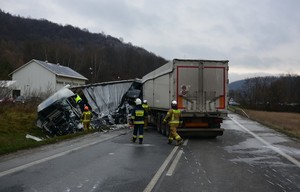 Ratownicy podczas działań na miejscu zderzenia ciężarówek w Lipowicy. W tle wraki zniszczonych pojazdów uczestniczących w wypadku