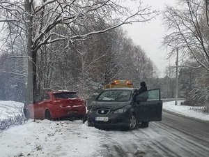 Na jezdni pokrytej śniegiem stoi pojazd marki Seat. Samochód ma rozbity przód z prawej strony. Za nim, poza jezdnią, znajduje się samochód marki Hyundai.