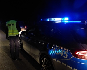 zdjęcie z miejsca wypadku, na którym widoczny jest policjant stojący obok radiowozu