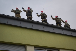 Policyjni antyterroryści z prezentami, w czapkach mikołajkowych zjeżdżają na linach z dachu budynku do szpitalnego okna