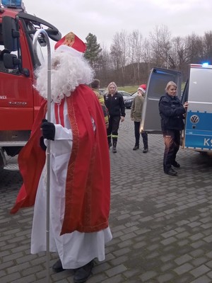 Święty Mikołaj obok policyjnego radiowozu.