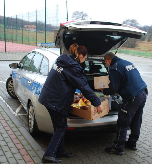 Funkcjonariusz i funkcjonariuszka wyjmują przygotowane produkty ze zbiórki z radiowozu