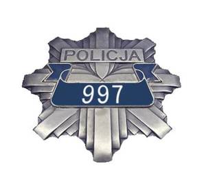 Na zdjęciu policyjna odznaka z napisem 997.