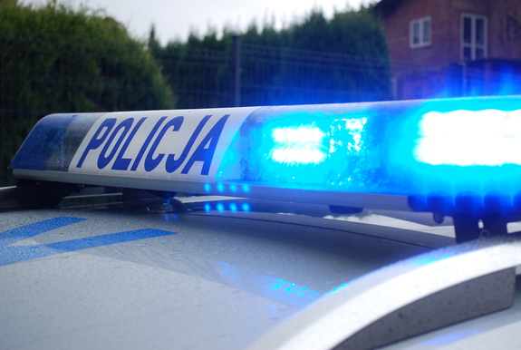 Na zdjęciu belka policyjnego radiowozu z włączonymi światłami barwy niebieskiej.