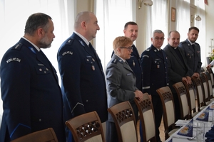 Policjanci podczas spotkania z rodzinami poległych policjantów. Uczestnicy spotkania dzielą się opłatkiem i składają sobie życzenia przy wigilijnym stole.