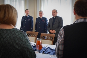 Policjanci podczas spotkania z rodzinami poległych policjantów. Uczestnicy spotkania dzielą się opłatkiem i składają sobie życzenia przy wigilijnym stole.