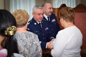 Policjanci podczas spotkania z rodzinami poległych policjantów. Uczestnicy spotkania dzielą się opłatkiem i składają sobie życzenia przy wigilijnym stole.