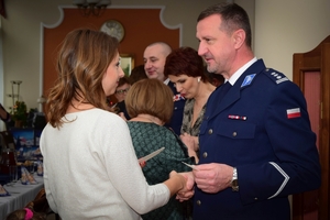 Policjanci podczas spotkania z rodzinami poległych policjantów. Uczestnicy spotkania dzielą się opłatkiem i składają sobie życzenia przy wigilijnym stole.