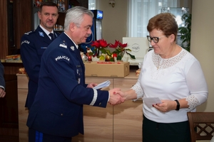 Policjanci podczas spotkania z rodzinami poległych policjantów. Uczestnicy spotkania dzielą się opłatkiem i składają sobie życzenia przy wigilijnym stole.