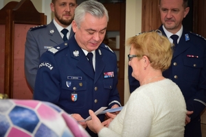 Policjanci podczas spotkania z rodzinami poległych policjantów. Uczestnicy spotkania dzielą się opłatkiem i składają sobie życzenia przy wigilijnym stole.