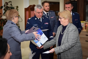 Policjanci podczas spotkania z rodzinami poległych policjantów. Uczestnicy spotkania dzielą się opłatkiem i składają sobie życzenia przy wigilijnym stole.