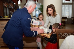 Policjanci podczas spotkania z rodzinami poległych policjantów. Uczestnicy spotkania dzielą się opłatkiem i składają sobie życzenia przy wigilijnym stole.