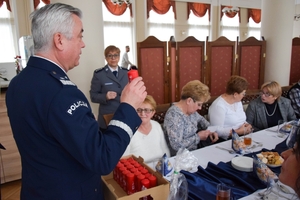 Policjanci podczas spotkania z rodzinami poległych policjantów. Uczestnicy spotkania dzielą się opłatkiem i składają sobie życzenia przy wigilijnym stole.
