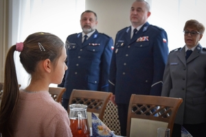 Policjanci podczas spotkania z rodzinami poległych policjantów. Uczestnicy spotkania dzielą się opłatkiem i składają sobie życzenia przy wigilijnym stole.