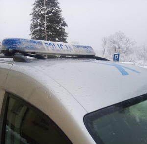 Oznakowany radiowóz policyjny w zimowej scenerii.