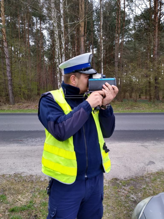policjant stoi przy drodze z urządzeniem do pomiaru prędkości