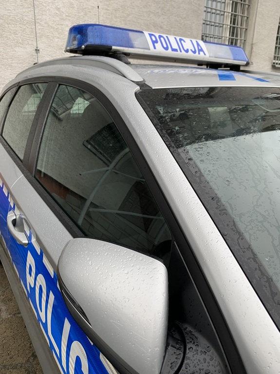 policyjny radiowóz w tle okno z metalową kratą
