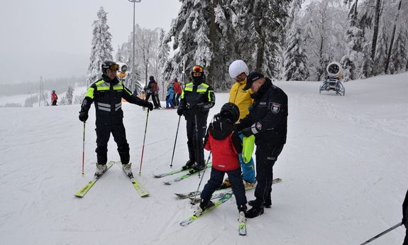Policjanci stoją na stoku w towarzystwie narciarzy