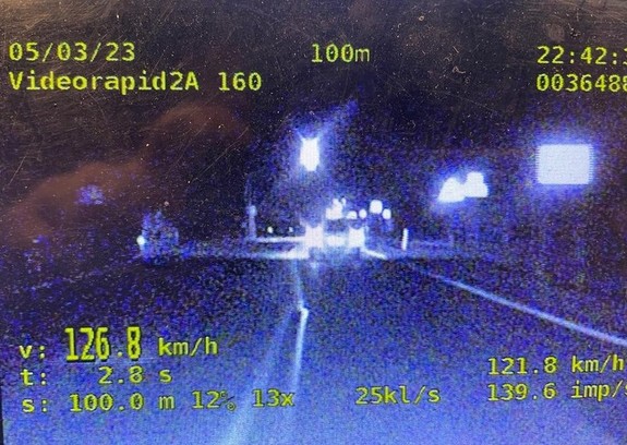 Kadr z nagrania wideorejestratora dokumentujący przekroczenie prędkości przez kierującego samochodem osobowym. W lewym dolnym rogu prędkość pojazdu 126,8 km/h.
