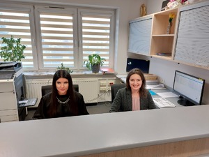 dwie kobiety siedzące za biurkiem