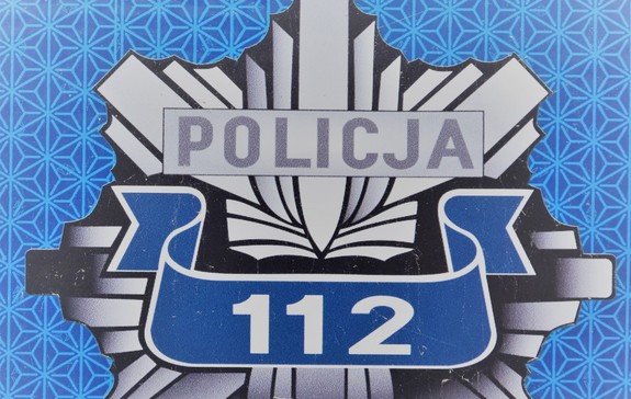 widoczna odznaka policyjna - napis POLICJA wraz z nr alarmowym 112