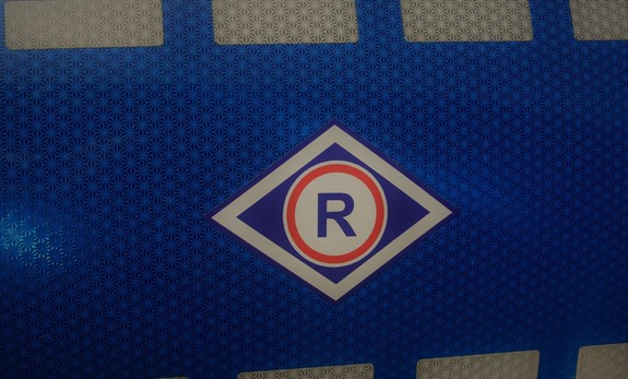 na zdjęciu widoczna litera R- oznaczająca Ruch Drogowy na policyjnym oznakowanym radiowozie