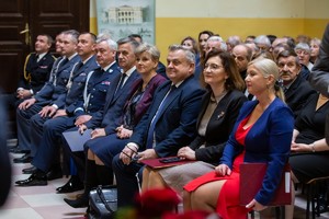 Uczestnicy uroczystości na dziedzińcu Zespołu Szkół w Tyczynie. Zaproszeni goście, przedstawiciele służb mundurowych siedzą w rzędach.