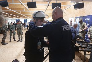 na zdjęciu widoczny jest policjant zakładający  kask na głowę  chłopakowi