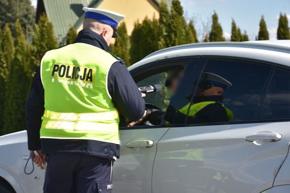 Na zdjęciu widoczny jest policjant sprawdzający stan trzeźwości kierującego samochodem osobowym.