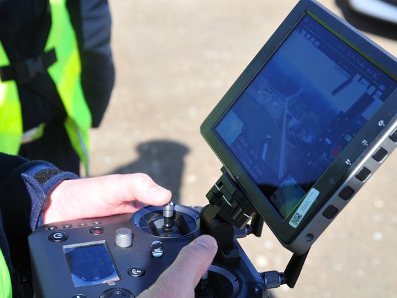 Na zdjęciu widoczny jest policjant trzymający kontroler do obsługi drona.