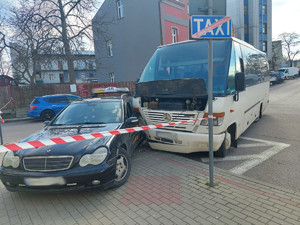 zdjęcie przedstawia samochody po zdarzeniu drogowym na ul. Sportowej w Przemyślu, biały bus (do przewozu osób) prawą przednia częścią uderzył w lewe tylnie drzwi czarnego mercedesa- taxi.