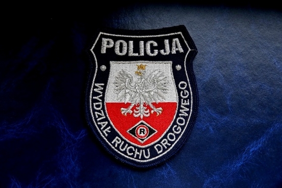 Naszywka z orłem na biało czerwonym tle i logotypem policjantów ruchu drogowego, w górnej części napis „policja”, wokół obrzeży napis „wydział ruchu drogowego”.