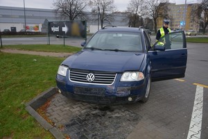 Policjant ruchu drogowego podczas oględzin uszkodzonego w zdarzeniu volkswagena