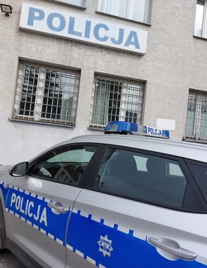 budynek na budynku napis policja przed budynkiem policyjny osobowy radiowóz z napisem policja