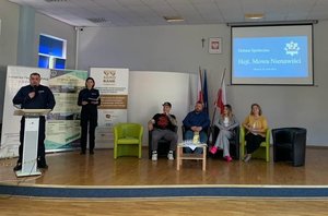 Na zdjęciu p.o. I zastępca Komendanta Powiatowego Policji w Lubaczowie kom. Daniel Rutkowski wita zaproszonych gości, przemawia z mównicy. W tle prelegenci debaty.