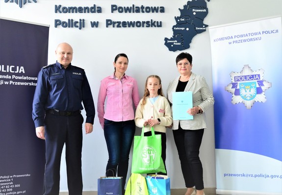 Wspólne zdjęcie laureatki konkursu z Komendantem Powiatowy Policji w Przeworsku rodzicem oraz opiekunem