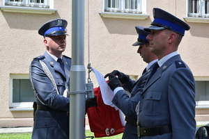 policjanci wciągający flagę na maszt przed komendą wojewódzką policji