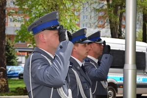 policjanci wciągają flagę na maszt przed komendą wojewódzką policji