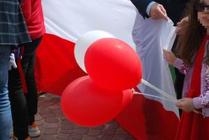 Na zdjęciu dziewczynka trzymająca białe i czerwone balony wśród tłumu ludzi.